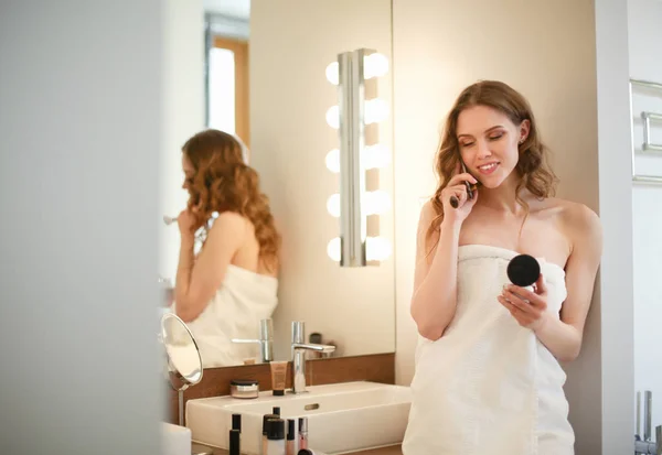 Jovem mulher de pé no banheiro com telefone . — Fotografia de Stock