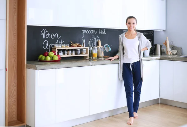 Mujer joven con jugo de naranja y tableta en la cocina. — Foto de Stock