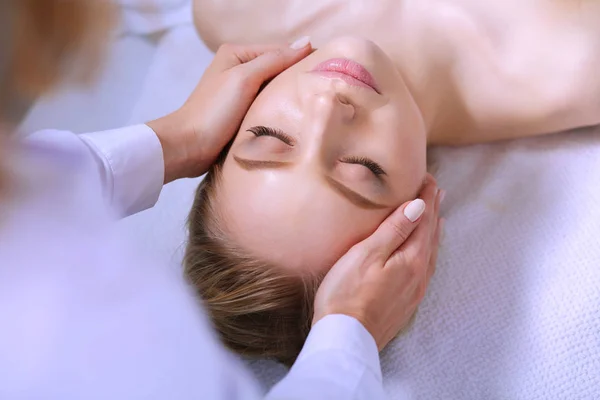 Mujer joven acostada en una mesa de masaje, relajándose con los ojos cerrados. Una mujer. Salón de spa — Foto de Stock