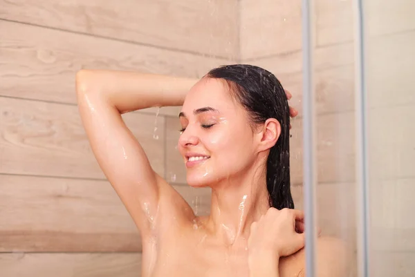Young beautyful woman under shower in bathroom. Stock Picture