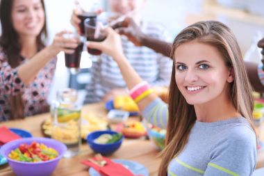 Ahşap masada otururken birlikte yemek yiyen bir grup insanın üst düzey görüntüsü. Masada yemek var. İnsanlar fast food yiyor. Bir kızın portresi.