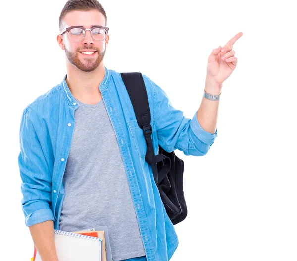 Un estudiante masculino con una bolsa de la escuela sosteniendo libros y señalando aislado sobre fondo blanco — Foto de Stock