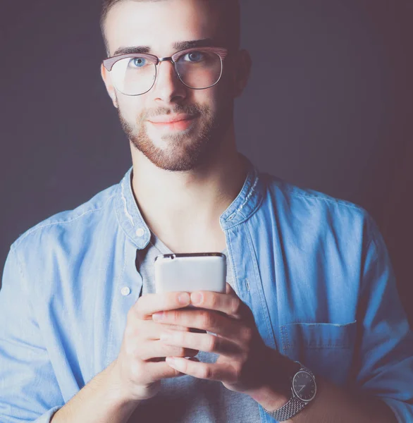 Ler ung man hålla telefonen medan textmeddelanden — Stockfoto