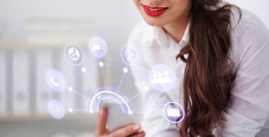 İş kadını ofiste akıllı telefonla mesaj gönderiyor.
