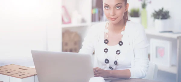 Atractiva mujer de negocios sentada en un escritorio con portátil en la oficina — Foto de Stock