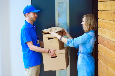 Mavi üniformalı gülümseyen kurye servis konseptine paket kutusu teslim eden teslimatçı.