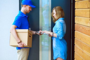 Mavi üniformalı gülümseyen kurye servis konseptine paket kutusu teslim eden teslimatçı.