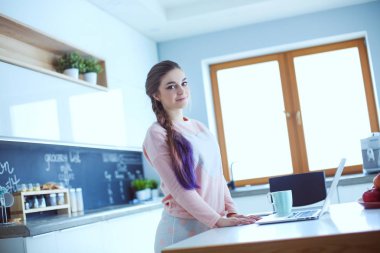 Cep telefonu ayakta modern mutfak kullanan kadın.