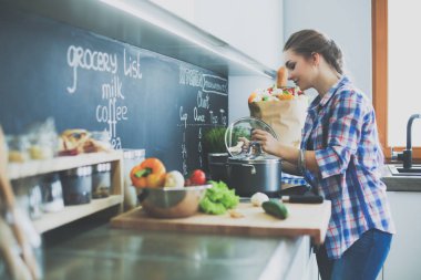 Mutfakta sobanın yanında duran genç bir kadın. .