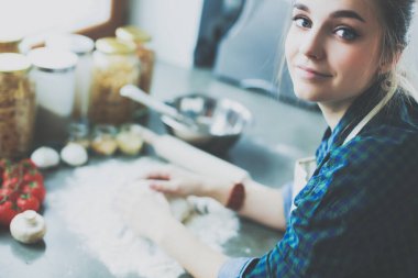 Mutfakta sobanın yanında duran genç bir kadın. .