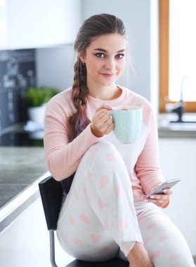 modern mutfakta otururken cep telefonu kullanan kadın.