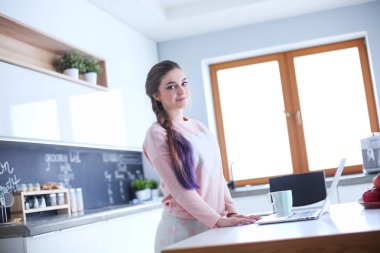 Cep telefonu ayakta modern mutfak kullanan kadın.