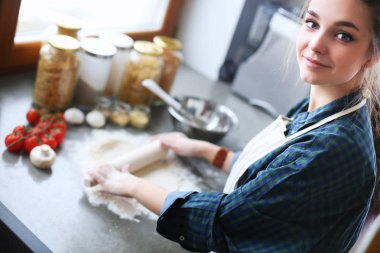 Güzel bir kadın mutfakta pasta pişiriyor. Masanın yanında duruyor..