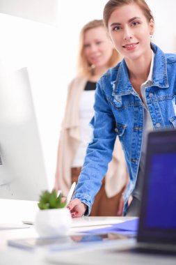 Masanın yanında duran iki genç kadın enstrüman, plan ve dizüstü bilgisayarla.