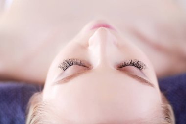 Masaj masasında uzanmış gözleri kapalı rahatlayan genç bir kadın. - Kadın. Spa salonu