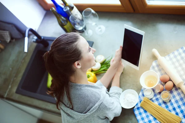 Güzel bir kadın mutfakta pasta pişiriyor. Masanın yanında duruyor..