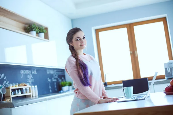 Femme utilisant un téléphone portable debout dans la cuisine moderne . — Photo