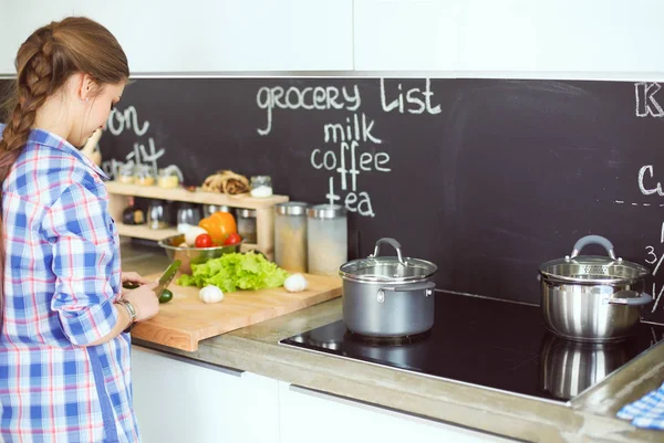 Mutfakta sobanın yanında duran genç bir kadın. .