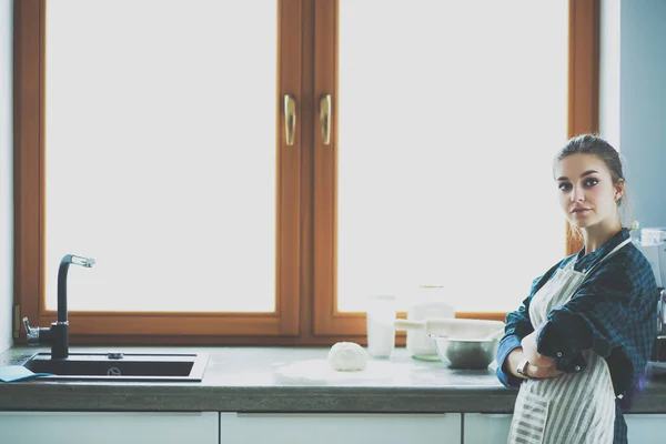 Mutfakta sobanın yanında duran genç bir kadın. . — Stok fotoğraf