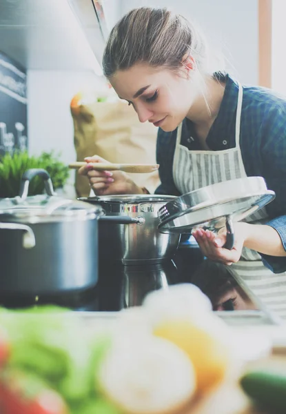 Jovem mulher em pé junto ao fogão na cozinha . — Fotografia de Stock