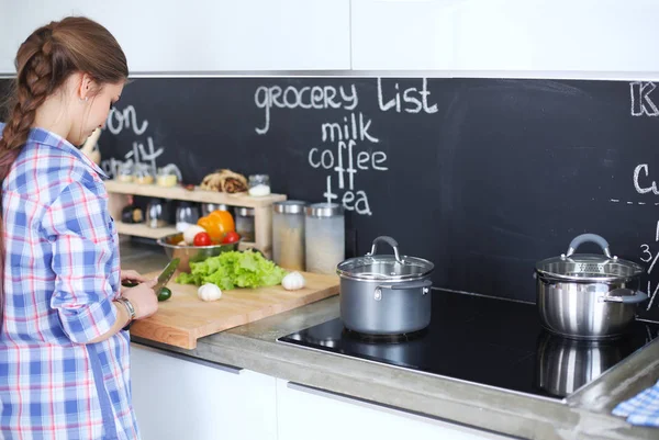 Mutfakta sobanın yanında duran genç bir kadın. .