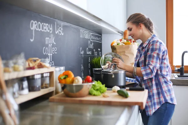 Mutfakta sobanın yanında duran genç bir kadın. .