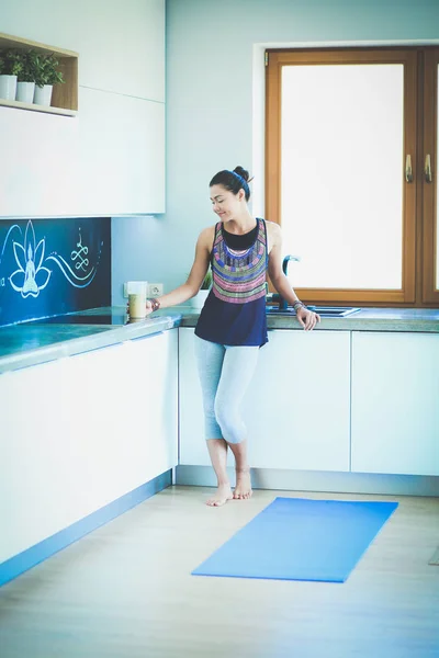 Retrato de una mujer sonriente sosteniendo en su mano una esterilla de yoga mientras estaba de pie en el estudio. Yoga. Una mujer. Bienestar — Foto de Stock