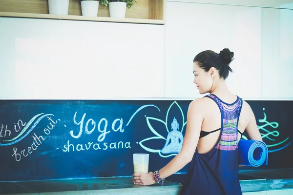 Retrato de una mujer sonriente sosteniendo en su mano una esterilla de yoga mientras estaba de pie en el estudio. Yoga. Una mujer. Bienestar — Foto de Stock