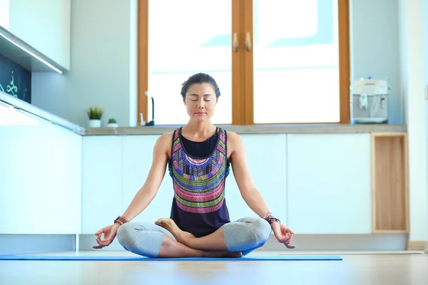 Mujer joven haciendo yoga en casa en la posición de loto. Yoga. Una mujer. Estilo de vida — Foto de Stock