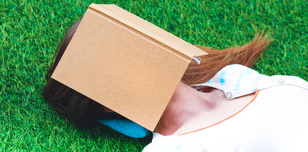 Beautiful young woman lying on green grass .