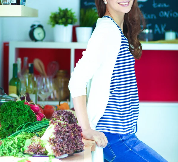 Genç bir kadın mutfakta duruyor.