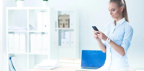 Joven mujer de negocios de pie en la oficina hablando en su teléfono móvil — Foto de Stock