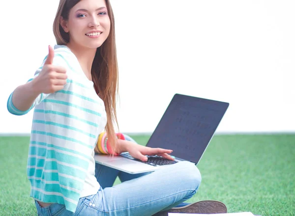 Ung kvinna med bärbar dator sitter på grönt gräs — Stockfoto