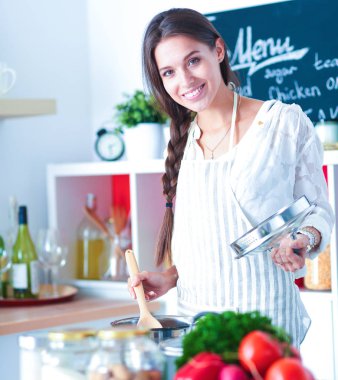 Mutfakta ahşap kaşıkla yemek pişiren kadın