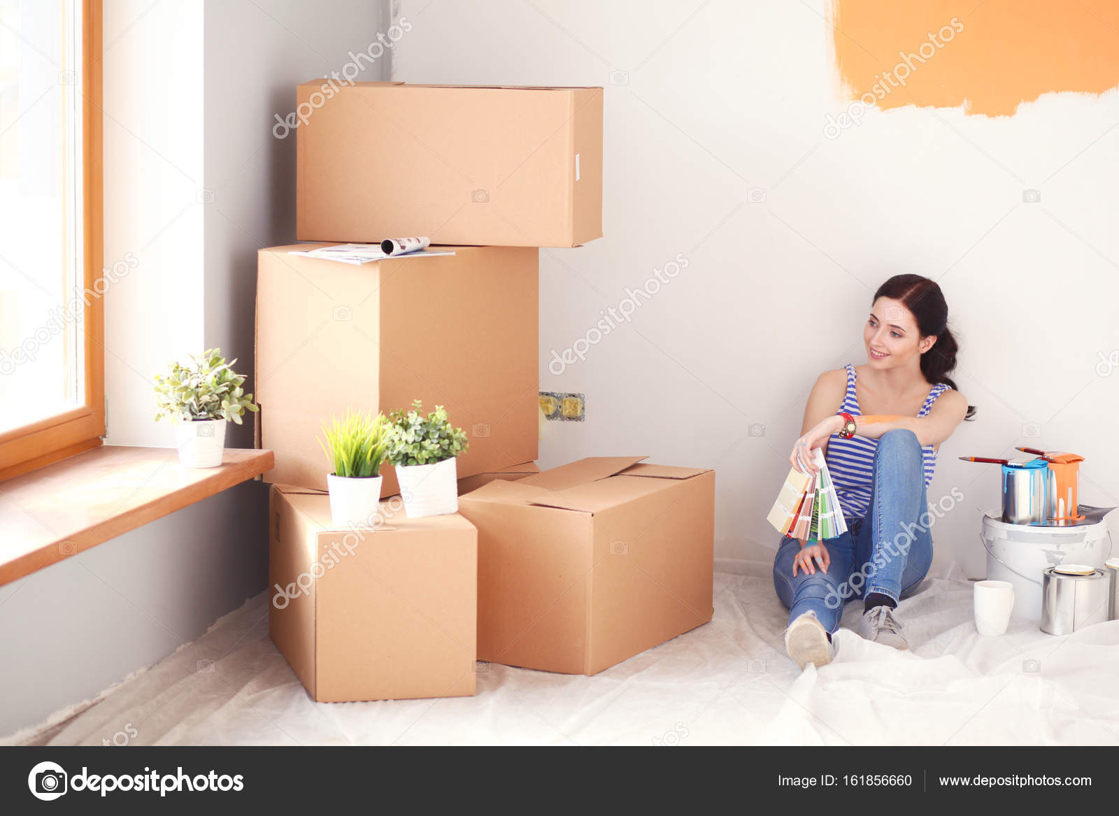 Woman Choosing Paint Colour From Swatch For New Home Sitting On