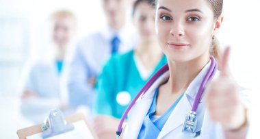 Genç, mutlu kadın doktor baş parmağını gösteriyor.