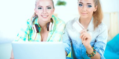 laptop ve kredi sepeti ile evde oturan iki genç kadın