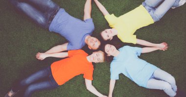 Bir grup genç insan yeşil çim üzerinde yalan
