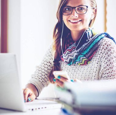 Kitapların arasında masa başında oturan genç bir kadın.