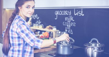 Mutfakta sobanın yanında duran genç bir kadın.