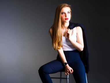 Genç bir kadın sandalyede oturuyor.