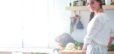 Mutfakta masanın yanında duran genç bir kadın.