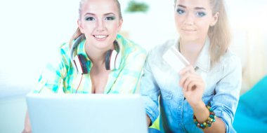 laptop ve kredi sepeti ile evde oturan iki genç kadın