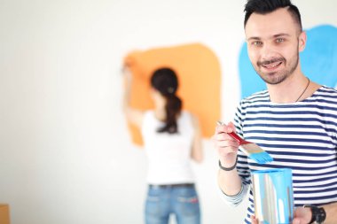 Yeni evin içini boyayan mutlu, genç bir çiftin portresi. Genç çift
