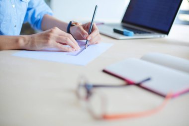 Ofis masasında dizüstü bilgisayarla oturan genç bir kadın. Genç bir kadın. Dizüstü bilgisayar