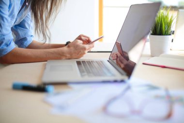 Ofis masasında oturan ve cep telefonuyla konuşan genç ve güzel bir iş kadını. İş kadını