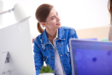 Masanın yanında duran iki genç kadın enstrüman, plan ve dizüstü bilgisayarla.