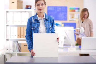 Masanın yanında duran iki genç kadın enstrüman, plan ve dizüstü bilgisayarla.