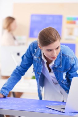 Masanın yanında duran iki genç kadın enstrüman, plan ve dizüstü bilgisayarla.