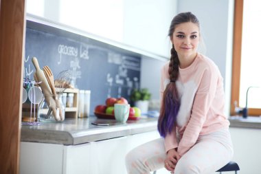 Mutfakta masada oturan genç kadın.